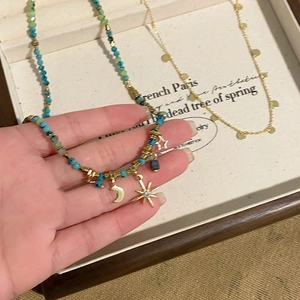 Detail of beaded star and moon necklace with sequins on a French style display tray
