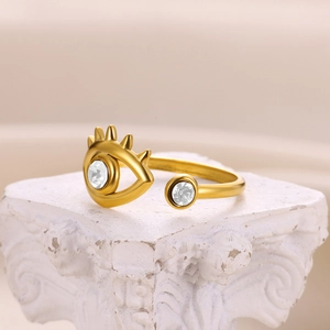 Detailed close-up of a gold Evil Eye ring with cubic zirconia on a white stone pedestal