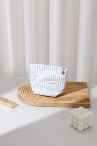 Vue détaillée de la trousse rayée avec fermeture éclair florale sur plateau en bois