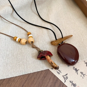 Close-up of vintage resin mushroom and red stone pendant necklaces with wooden beads