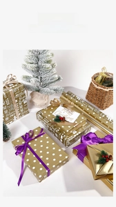Detail of Christmas wrapping paper with gold polka dots, white festive patterns and ribbons