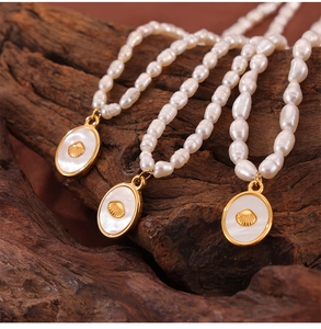Detail of baroque pearl necklace featuring gold oval pendants with white shell inlay