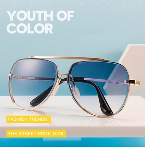 Detail of pilot sunglasses with gold metal frame and blue gradient lenses on a pedestal