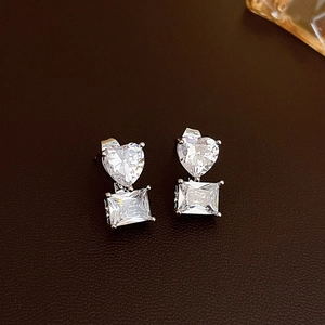Detail view of heart and rectangular cut crystal earrings in a silver-tone claw setting