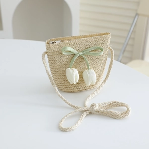 Detail of straw woven crossbody bag featuring light green ribbon and tulip pendants