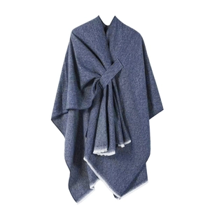 Detail of dark blue knit poncho featuring a front knot design and white tassel fringe