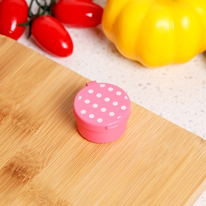 Close-up of pink polka dot sauce container on a wooden board in a kitchen setting