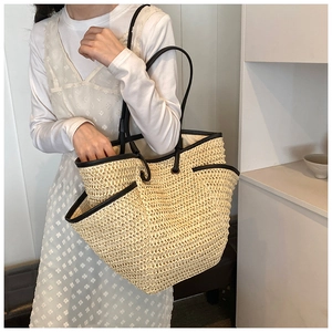Detail of hand-woven straw tote with black leather trim and handles for summer