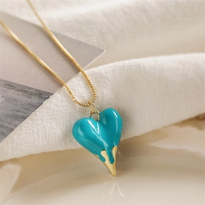 Detail of teal heart pendant with melting gold effect on a fine gold-colored chain