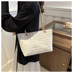 Detail of white tweed tote bag with classic plaid pattern and metallic chain strap