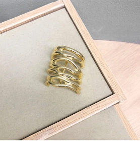 Macro shot of minimalist gold wave hairpin with multilayer liquid metal texture on grey tray