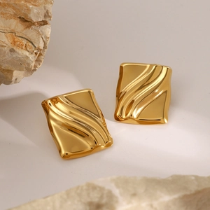 Macro shot of gold-plated rectangular earrings with wave texture on stone
