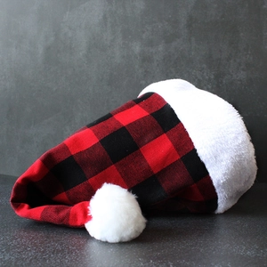 Festliche rot-schwarze Weihnachts mütze mit Karomuster und weißem Plüschrand und Bommel