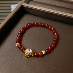Detailed close-up of red beaded crystal bracelet with gold heart charm and zircon stones