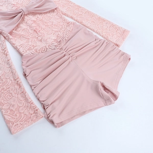 Detail of pink lace stitching and decorative bow on long sleeve jumpsuit