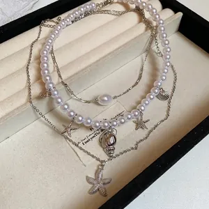 Three-layer layered necklace featuring starfish and shell pendants with elegant white pearls