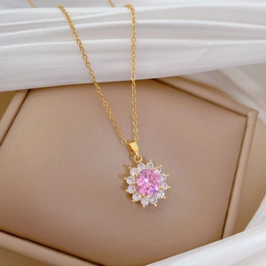 Detailed view of a gold flower necklace with a pink gemstone on soft silk fabric