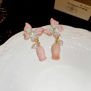 Boucles d'oreilles pendantes papillon émaillé et perles sur une assiette vintage