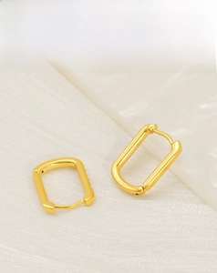 Macro shot of gold-plated rectangular hoop earrings with delicate zircon stones