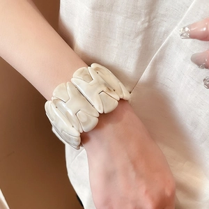 Detail of wide ivory resin bracelet with H-link chain and marble pattern finish