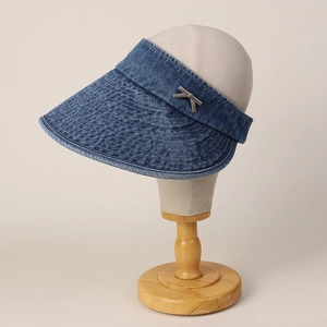 Detailed stitching and metallic logo accent on the brim of a denim open-top sun hat