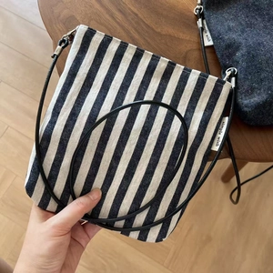 Detail of vintage striped canvas crossbody bag with metal buckle and simple wish tag