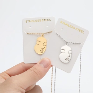 Detail of abstract face necklaces in 18K gold and silver plated stainless steel finish