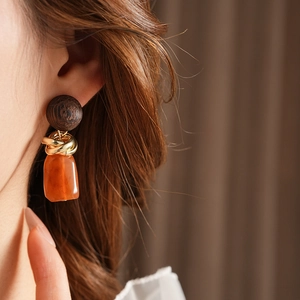 Close-up of vintage geometric earrings with dark wood, gold metal and resin on model