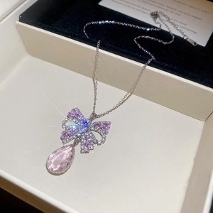 Macro view of butterfly bow pendant with purple and pink crystals on black velvet