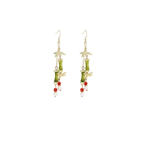 Detail of elegant gold earring with green bamboo joints and hanging red pearl beads