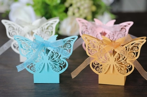 Detail of laser-cut butterfly wedding favor boxes in blue, gold, pink, and white paper