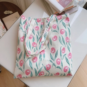 Gros plan du sac en coton à fleurs roses avec poignées tissées sur un bureau blanc