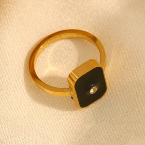 Detailed top view of a gold square ring with a black enamel inlay and small zircon stone