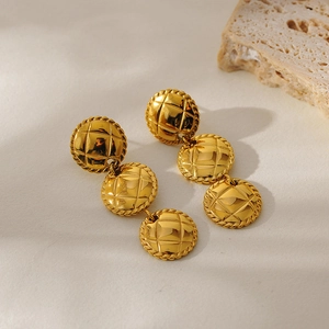 Minimalist gold tiered disc drop earrings with quilted texture on stone background