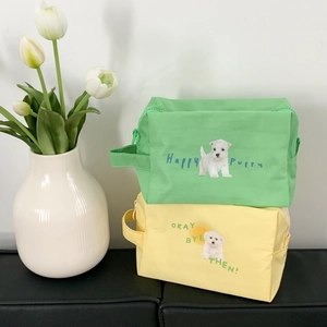 Detail of dog print makeup bags with Happy Puppy text and side handles in soft lighting
