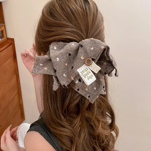 Detailed back view of a brown polka dot fabric hair tie with wood button and label