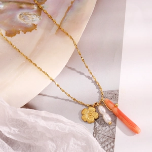 Detail of 18K gold plated necklace featuring floral pendant, pearls, and coral bead