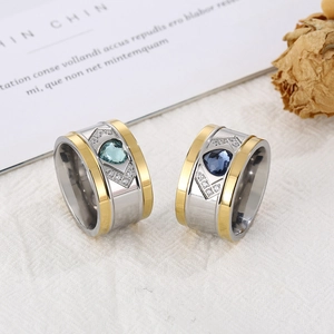 Elegant wide mixed-gold ring set with crystal heart stones on a white fabric background