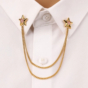 Detail of star collar pins with pink gems and gold chains on a white shirt