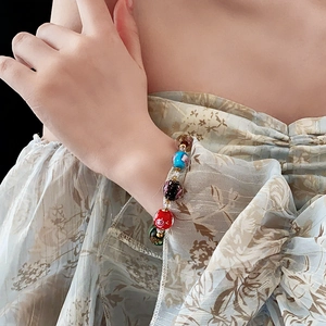 Detailed view of a colorful glass bead bracelet worn by a model on a dark background