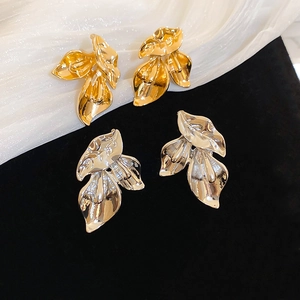 Detailed view of layered metallic flower stud earrings in gold and silver mirror finish