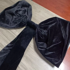 Detailed view of a large black velvet decorative bow on light wood background