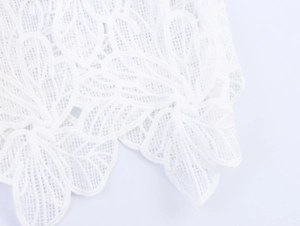 Close-up of elegant white lace fabric with intricate floral embroidery and scalloped edges