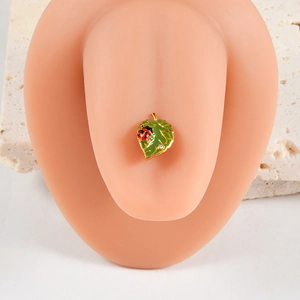 Vue macro d'un piercing feuille émaillée verte et coccinelle sur modèle en silicone