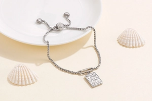 Close-up of adjustable silver box chain bracelet with engraved rectangular pendant detail