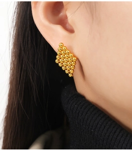 Detail of geometric gold bead cluster earrings on a model with vintage Italian style
