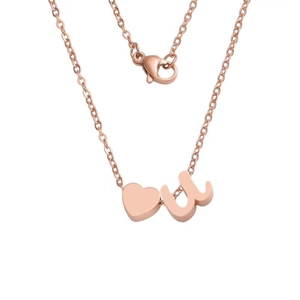 Detail of rose gold heart pendant and lowercase letter u charm on a delicate chain