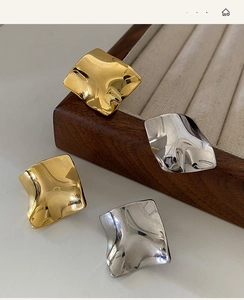 Detailed view of irregular wavy gold and silver metal earrings on a jewelry display tray