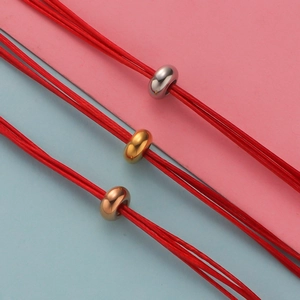 Detailed view of woven red cord bracelets with gold, silver, and rose gold beads