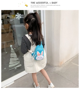 Detail shot of a blue bunny-themed fabric chest bag worn by a child in a cafe setting